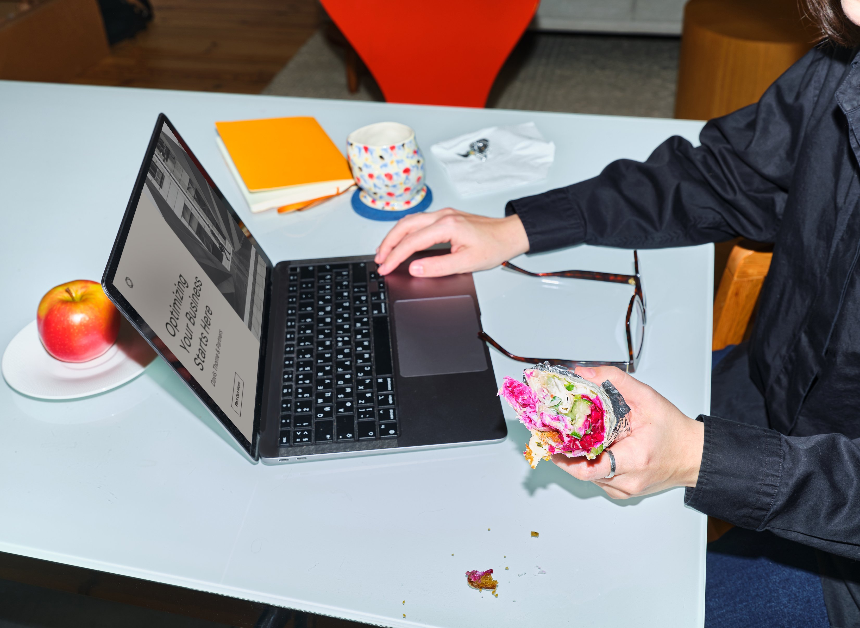 Graphic Designer Eating Snacks While Working on a Laptop